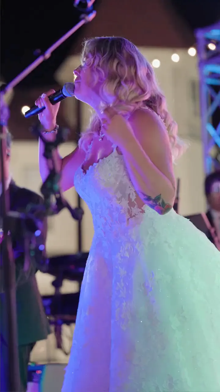 Jenna singing into a microphone on stage
