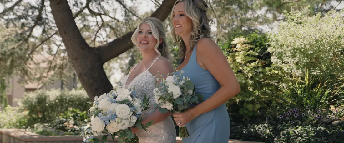 The bride and a bridesmaid beneath an oak tree in the gardens at Maravilla Gardens