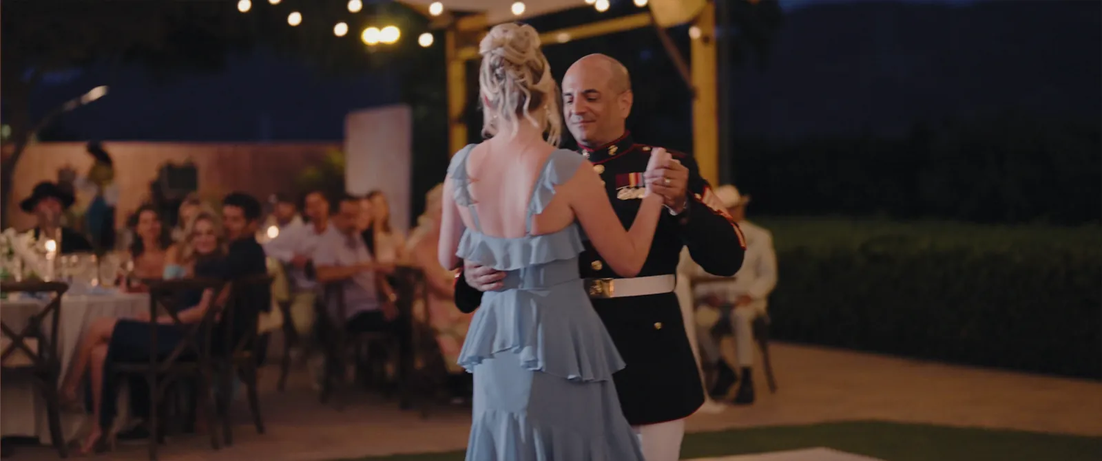 A couple dancing under string lights at their wedding reception